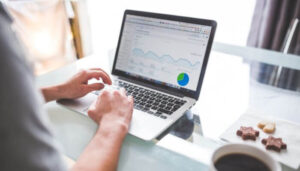 Imagem representado uma pessoa usando seu notebook em cima da mesa mostrando a tela do analytics do Google referente a anúncios do Instagram.