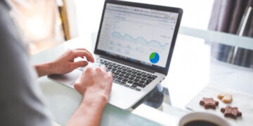 Imagem representado uma pessoa usando seu notebook em cima da mesa mostrando a tela do analytics do Google referente a anúncios do Instagram.