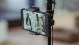 Foto de um smartphone em um suporte, gravando um vídeo de duas mulheres conversando, representando as melhores estratégias para criar conteúdo no Instagram em 2024.
