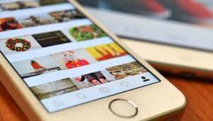 Foto de um smartphone mostrando a interface do Instagram com várias imagens no feed, representando como marcar alguém no Instagram em posts, Stories e comentários.