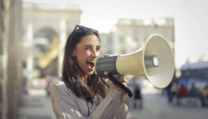 Foto de uma mulher usando um megafone, representando uma estratégia de divulgação no Instagram.