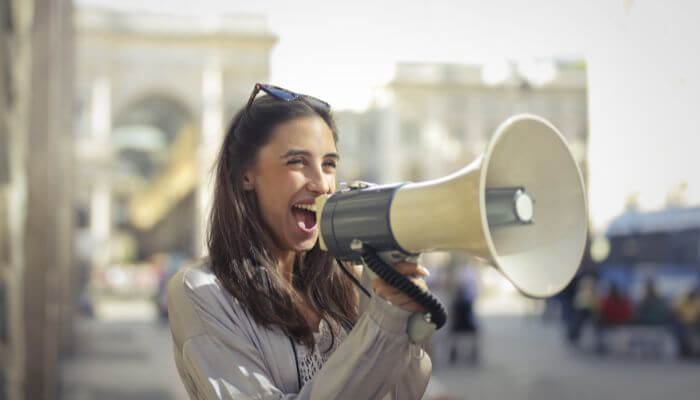 Foto de uma mulher usando um megafone, representando uma estratégia de divulgação no Instagram.