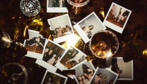 Foto de várias polaroides espalhadas sobre uma mesa com taças de vinho e decorações, representando ideias criativas de fotos para ter um perfil atrativo no Instagram.