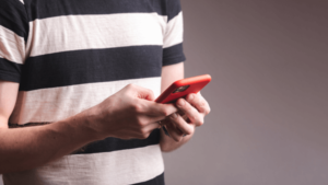 Homem de camisa listrada com celular nas maos