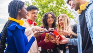 Grupo de jovens segurando smartphones e usando fones de ouvido coloridos, representando como colocar música no Instagram em posts, Stories e Reels.