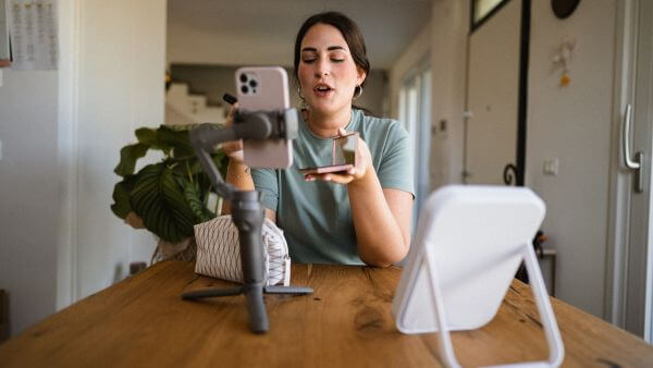 Mulher em uma mesa gravando para o celular