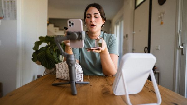 Mulher criando conteúdo digital gravando um vídeo com smartphone em casa.