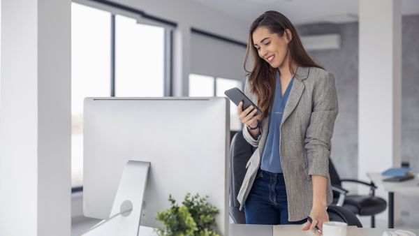 Profissional olhando para celular feliz após encontrar bons nomes para Instagram feminino